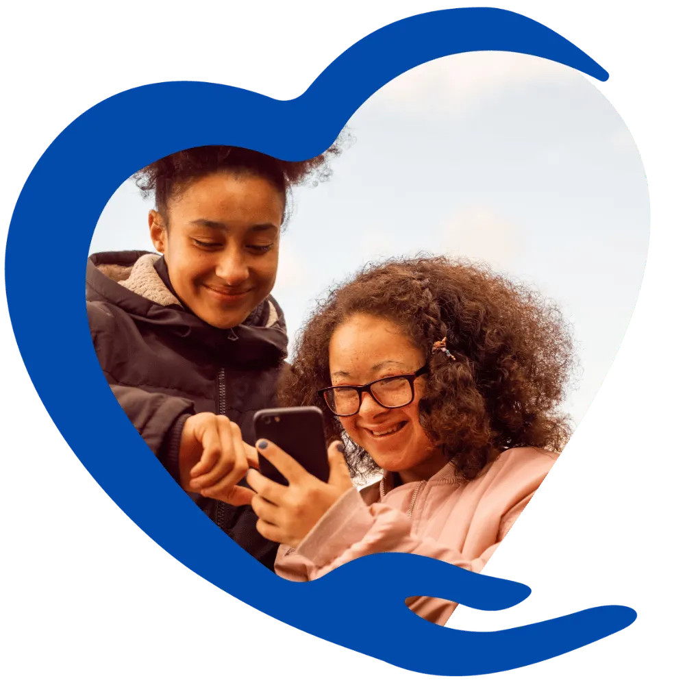 Disabled girl holding mobile phone with friend and smiling